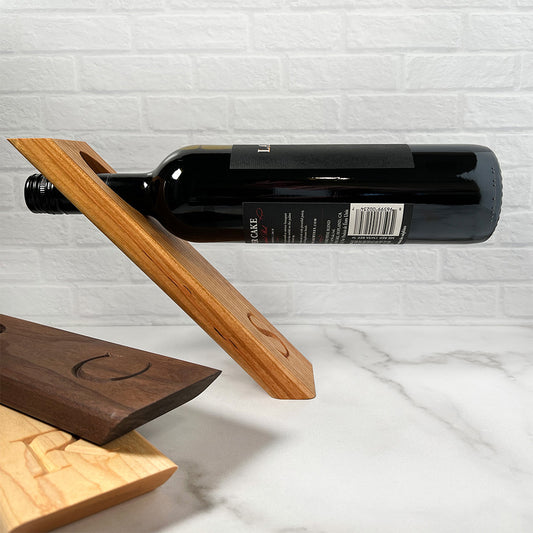 A balancing wine bottle holder with a wooden cutting board.