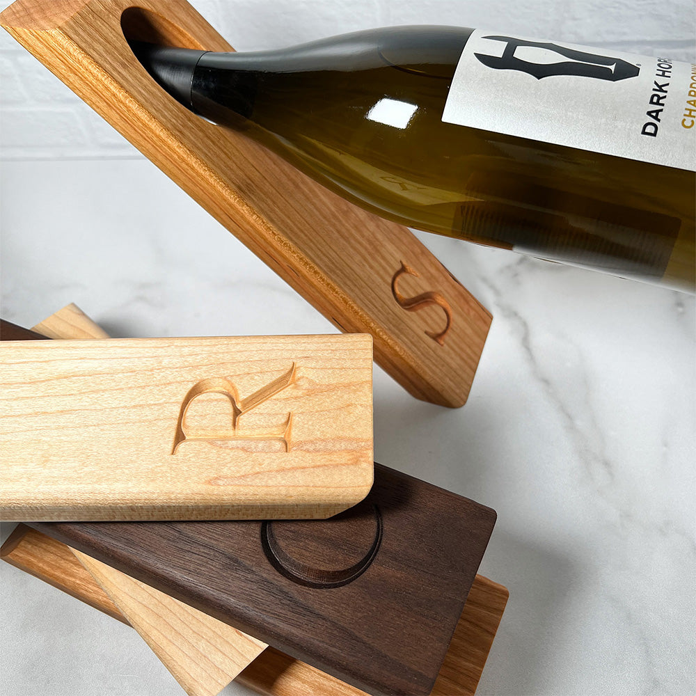 A wooden Balancing wine bottle holder with a bottle of wine on it.