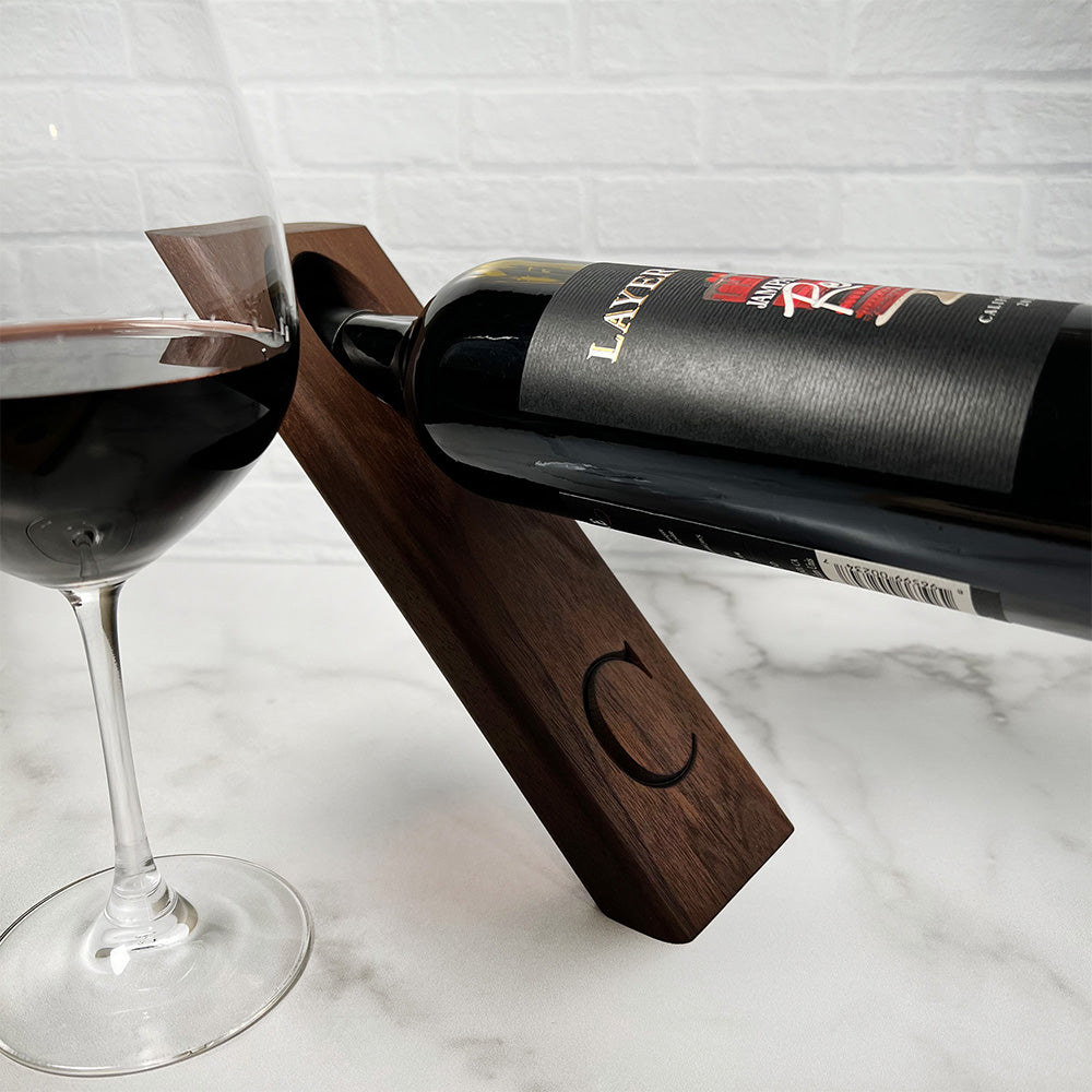 A Balancing wine bottle holder with a glass of wine.