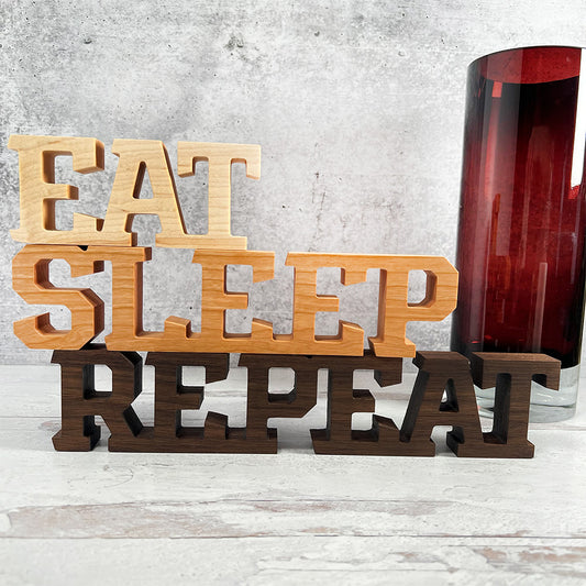 A wooden sign that says Standing words - Eat Sleep Repeat.