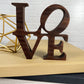 A wooden sign with the Standing word - LOVE on top of a book.