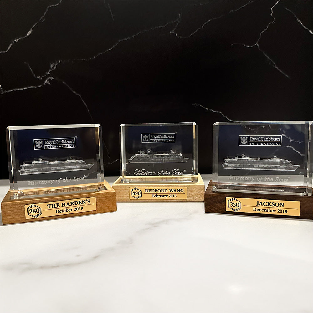 Three Cruise Milestone crystal block base awards on a marble table.
