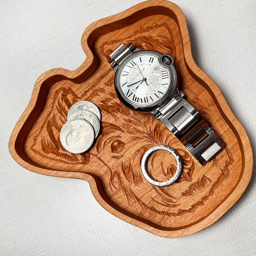 A Schnauzer wood tray with a watch and coins on it.