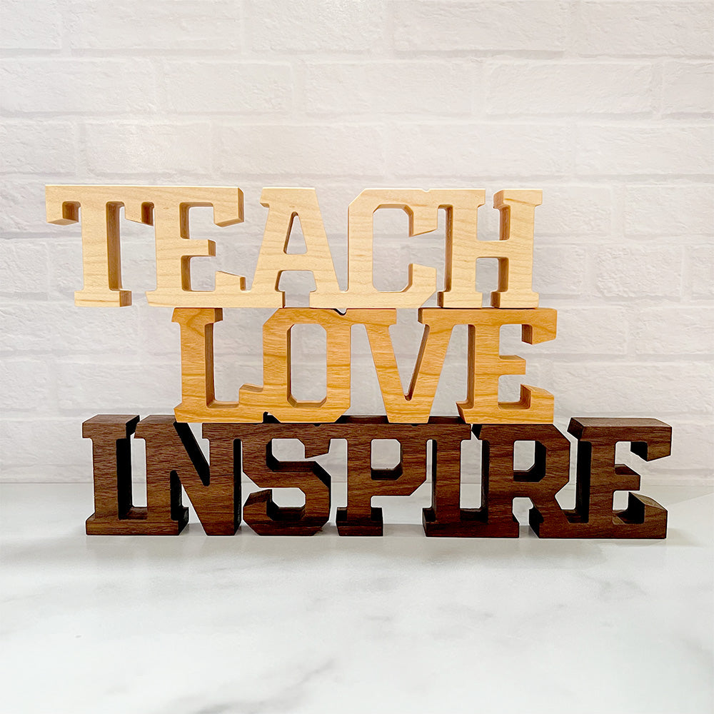 A wooden sign that says standing words - Teach Love Inspire.